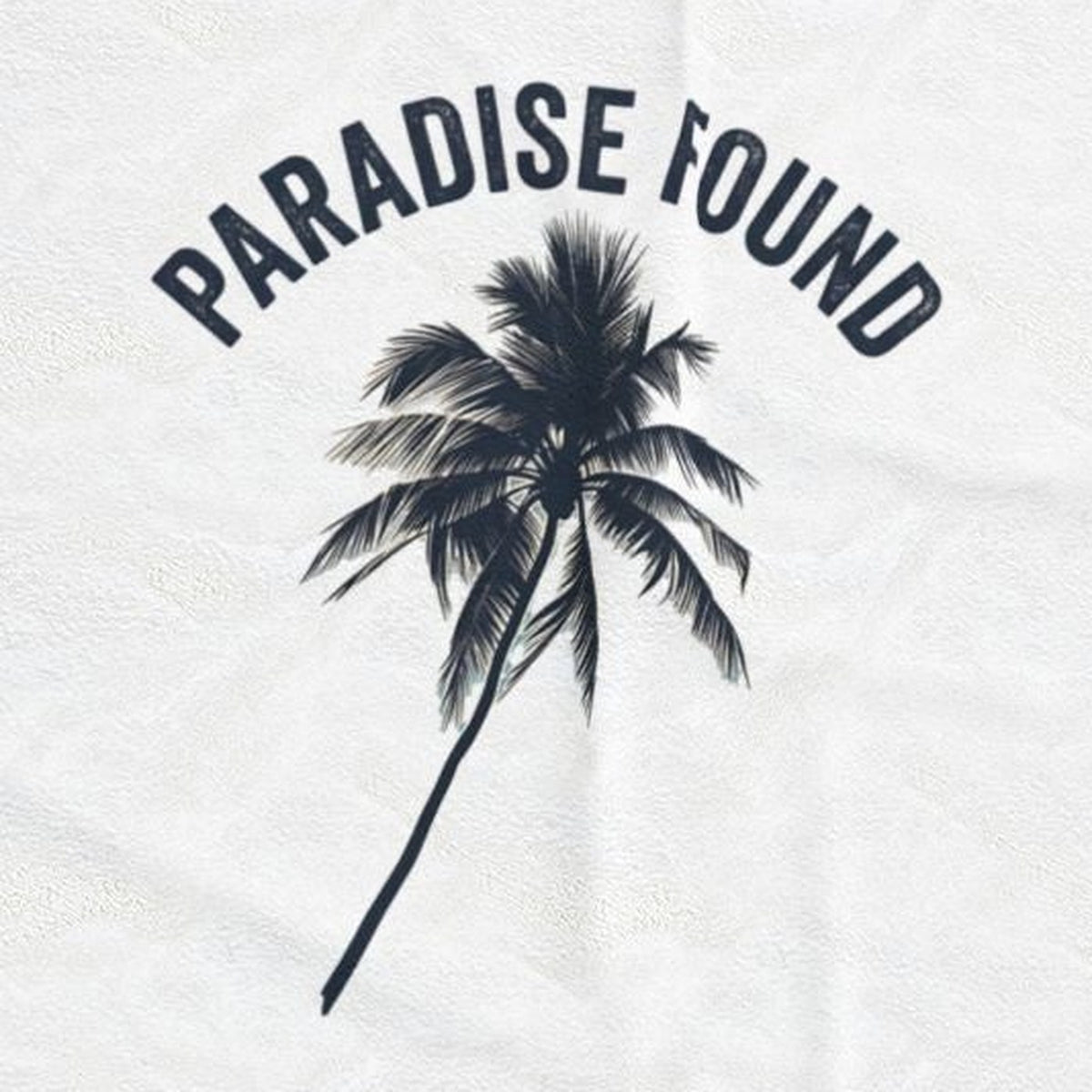 Close-up of the Paradise Found print: a single dark palm silhouette under arched lettering, on the white velveteen throw